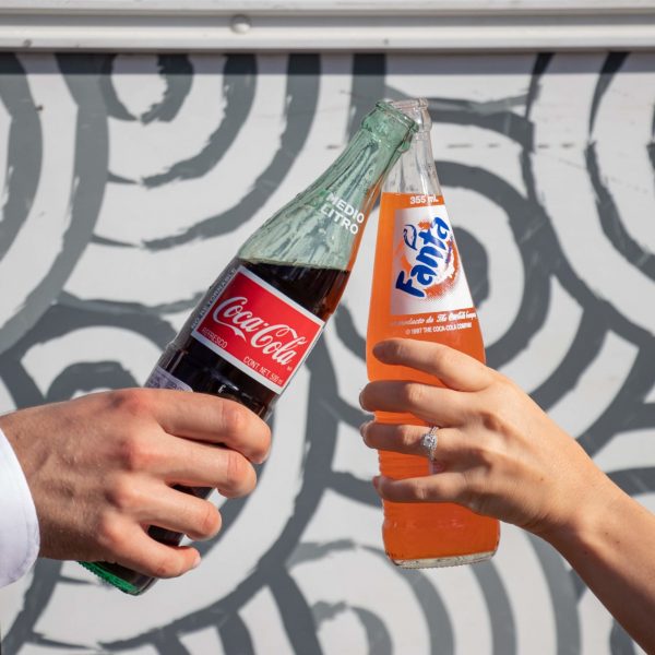 A newlywed couple clinking bottles of soda together, enjoying their wedding catering in Phoenix, AZ